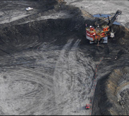 Zoomed image showing excavator, and dump
 truck hauling away spoil and oil/tar sands. Image: Edward Burtynsky